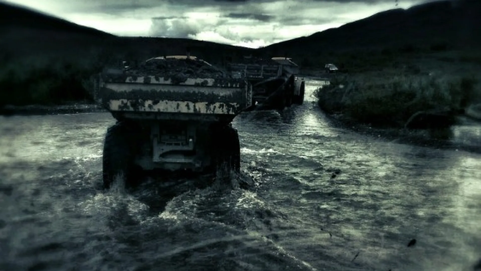 Haul trucks crossing water, viewed from a equipment cab