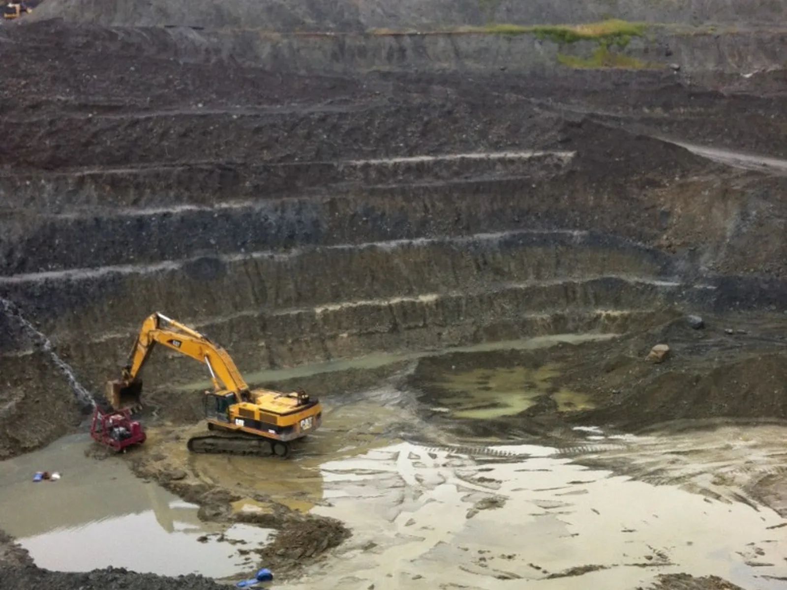 Caterpillar excavator working a muddy open-pit mine